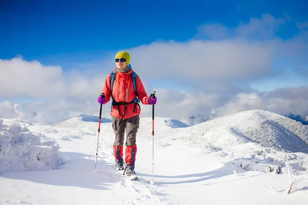 Fille avec sac à dos marchant sur la neige dans les montagnes . — Photo