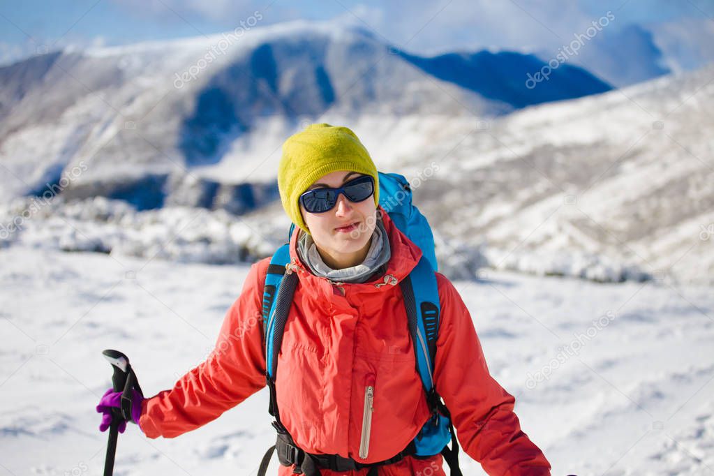 Girl with backpack walking on snow in the mountains.