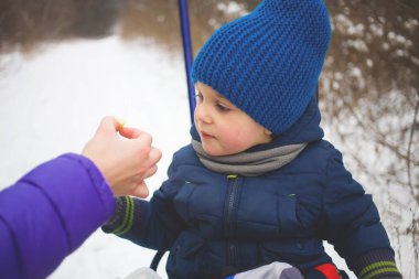 Kızak ve bir elma yemek çocuk oturur.