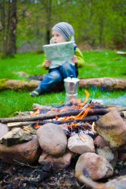 Bir kamp ateşi oturan harita çocukla.