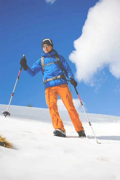 Hombre con bastones de trekking pasa por la nieve en las montañas . — Foto de Stock