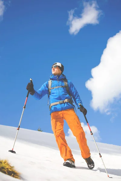 Mannen med vandringsstavar går genom snön i fjällen. — Stockfoto