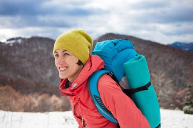 Dağlarda kar üzerinde yürüyen sırt çantası ile kız.