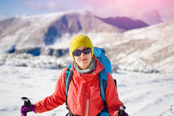 Dağlarda kar üzerinde yürüyen sırt çantası ile kız.