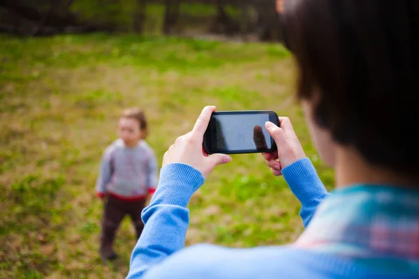 Девушка делает фото ребенка на смартфоне . — стоковое фото