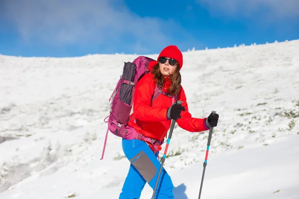 Fille avec sac à dos marchant sur la neige dans les montagnes . — Photo