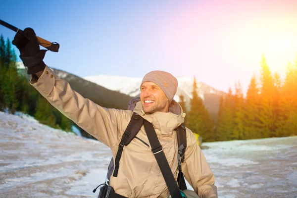 Um homem é fotografado no fundo de montanhas nevadas . — Fotografia de Stock