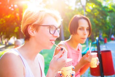 İki kız parkta kahve içme.