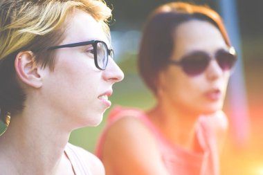 Parkta bir bankta oturan iki genç kadın.