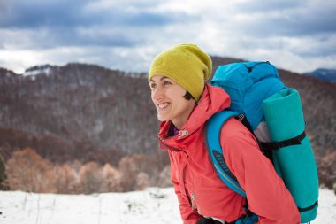 Dağlarda kar üzerinde yürüyen sırt çantası ile kız.