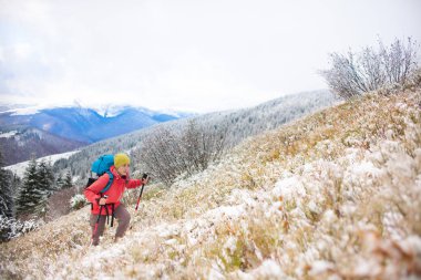 Dağlarda kar üzerinde yürüyen sırt çantası ile kız.