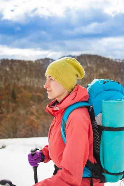 山の雪の上を歩いてのバックパックを持つ少女. — ストック写真