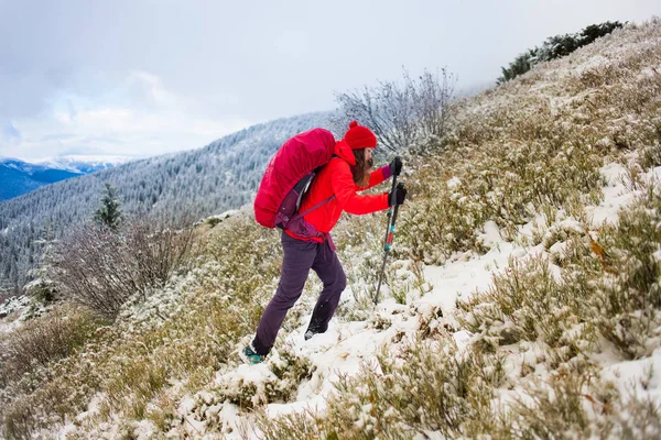 Fille avec sac à dos marchant sur la neige dans les montagnes . — Photo