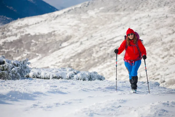 Chica con mochila caminando en la nieve en las montañas . — Foto de Stock