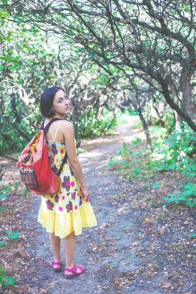 Chica con una mochila caminando por el bosque . — Foto de Stock