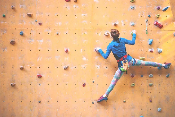 La fille grimpe sur le mur d'escalade . — Photo