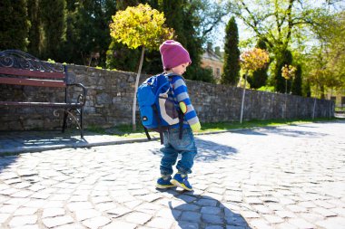 Bir çocuk sokakta yürüyen bir sırt çantası ile.