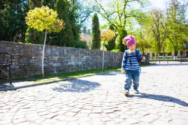Bir çocuk sokakta yürüyen bir sırt çantası ile.