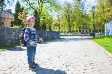 Bir çocuk sokakta yürüyen bir sırt çantası ile.