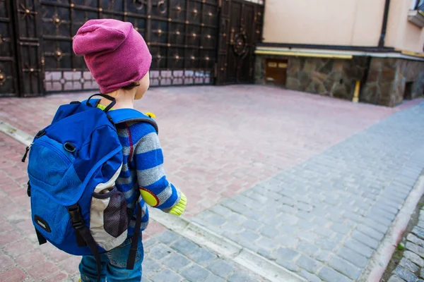 En pojke med en ryggsäck som går tvärs över gatan. — Stockfoto