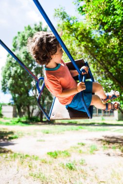 Çocuk salıncakta eğleniyor.