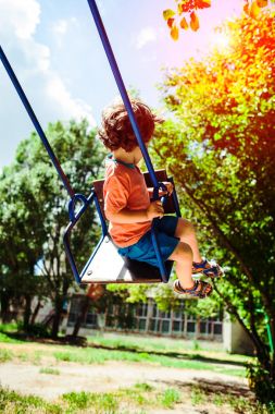 Çocuk salıncakta eğleniyor.