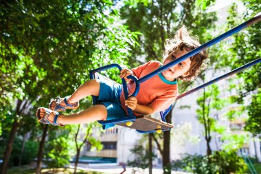 Çocuk salıncakta eğleniyor.