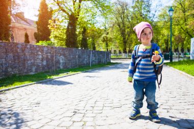 Bir çocuk sokakta yürüyen bir sırt çantası ile.