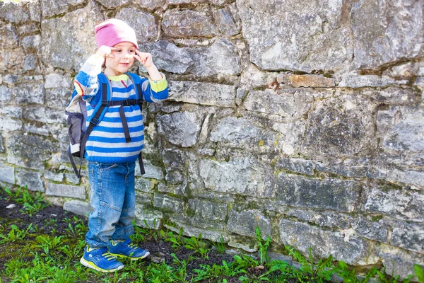 石の壁近くに立っているバックパックを持つ少年. — ストック写真