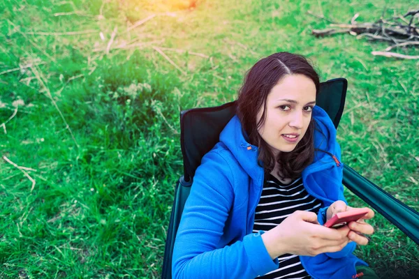 Девушка в природе смотрит в мобильный телефон . — стоковое фото