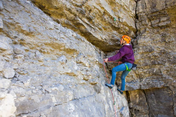 Kvinnan i hjälmen klättrar rock. — Stockfoto