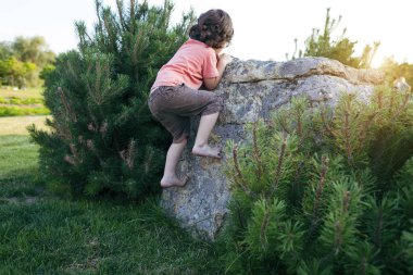 Çocuk taşa tırmanıyor.