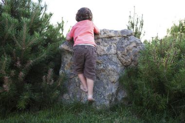 Çocuk taşa tırmanıyor.