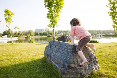 Çocuk taşa tırmanıyor.