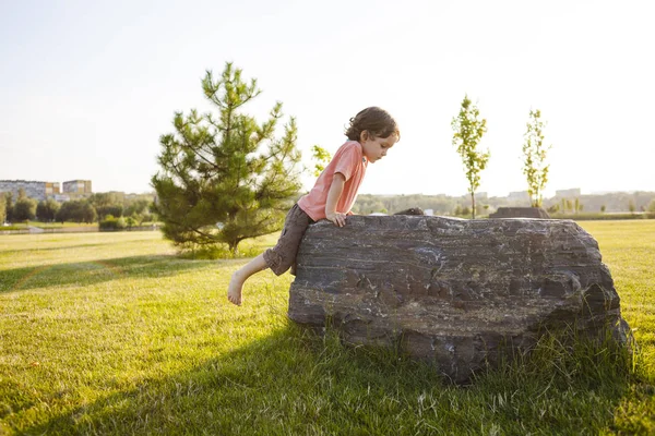 Pojken klättrar på stenen. — Stockfoto