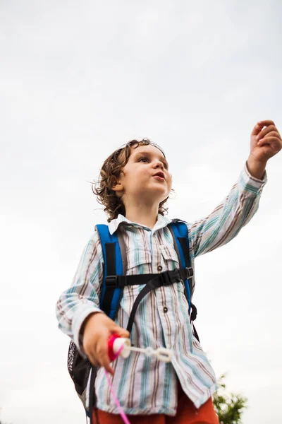 Um menino está brincando com bolhas de sabão . — Fotografia de Stock