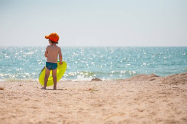 Çocuk sahilde yürüyor.