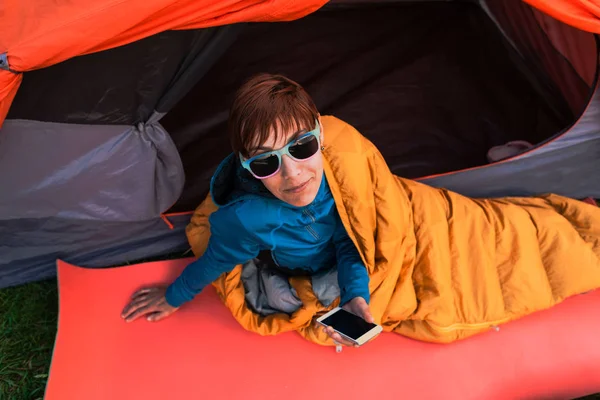 Menina com um telefone em um saco de dormir . — Fotografia de Stock