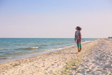 Bir kız sahilde yürüyor.