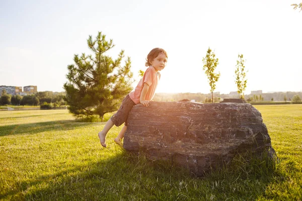 Çocuk taşa tırmanıyor.