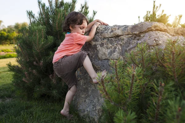 Çocuk taşa tırmanıyor.