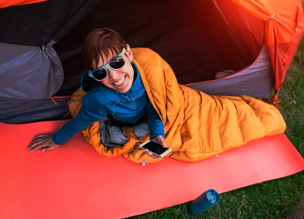 Chica con un teléfono en un saco de dormir . — Foto de Stock