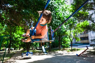Çocuk salıncakta eğleniyor.