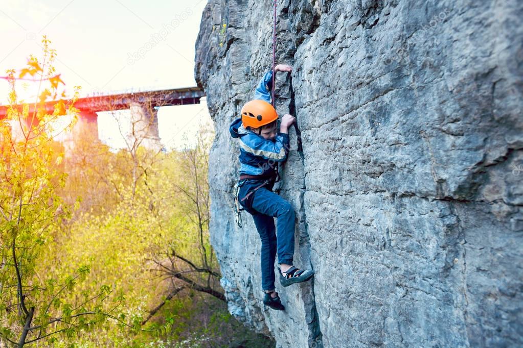 Kid rock climber climbs the cliff.