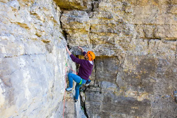 A nő a sisak felmászik a rock. — Stock Fotó