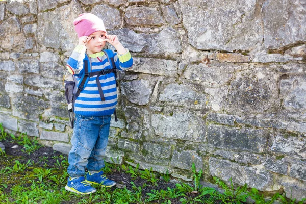 石の壁近くに立っているバックパックを持つ少年. — ストック写真