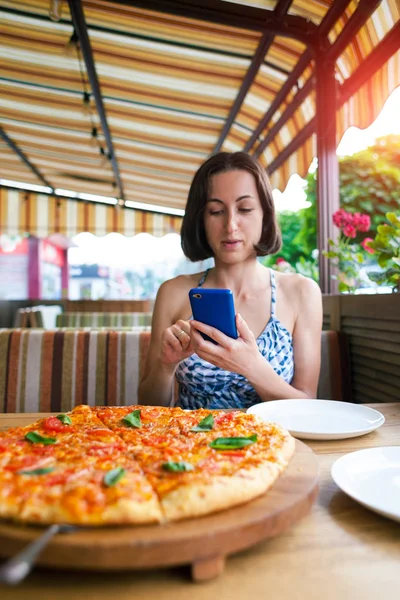 Kız telefonla pizza fotoğrafları yapma.