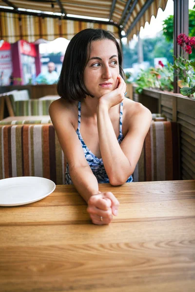 Uma menina está esperando por sua ordem em um café . — Fotografia de Stock