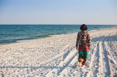 Bir kız sahilde yürüyor.