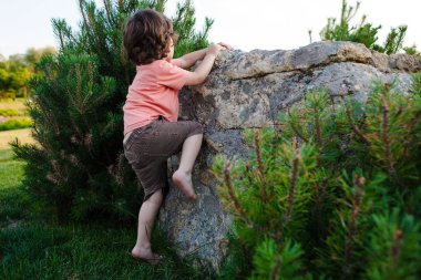 Çocuk taşa tırmanıyor.